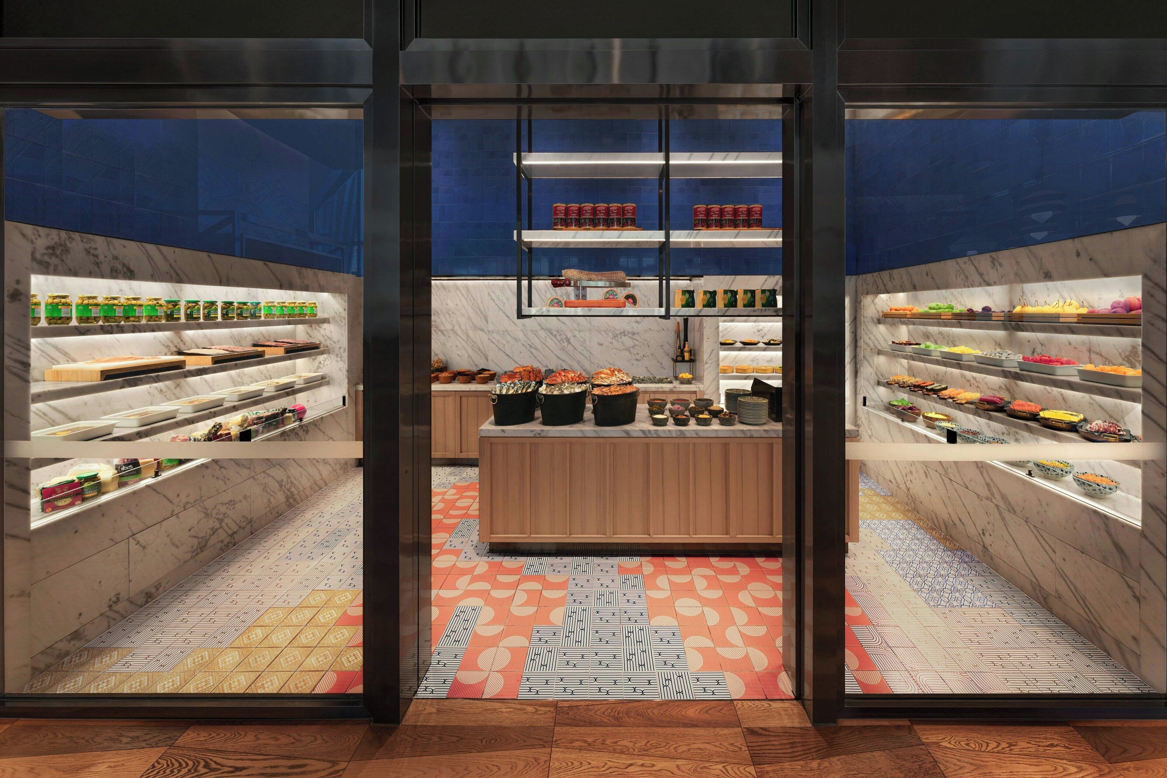 Un interior moderno con paredes de mármol, estantes llenos de alimentos y un suelo estampado.