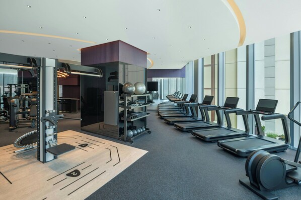 A modern gym with treadmills, weight machines, and a mirrored wall.
