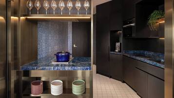 A modern kitchen with a blue marble countertop, a built-in oven, and a stainless steel refrigerator.