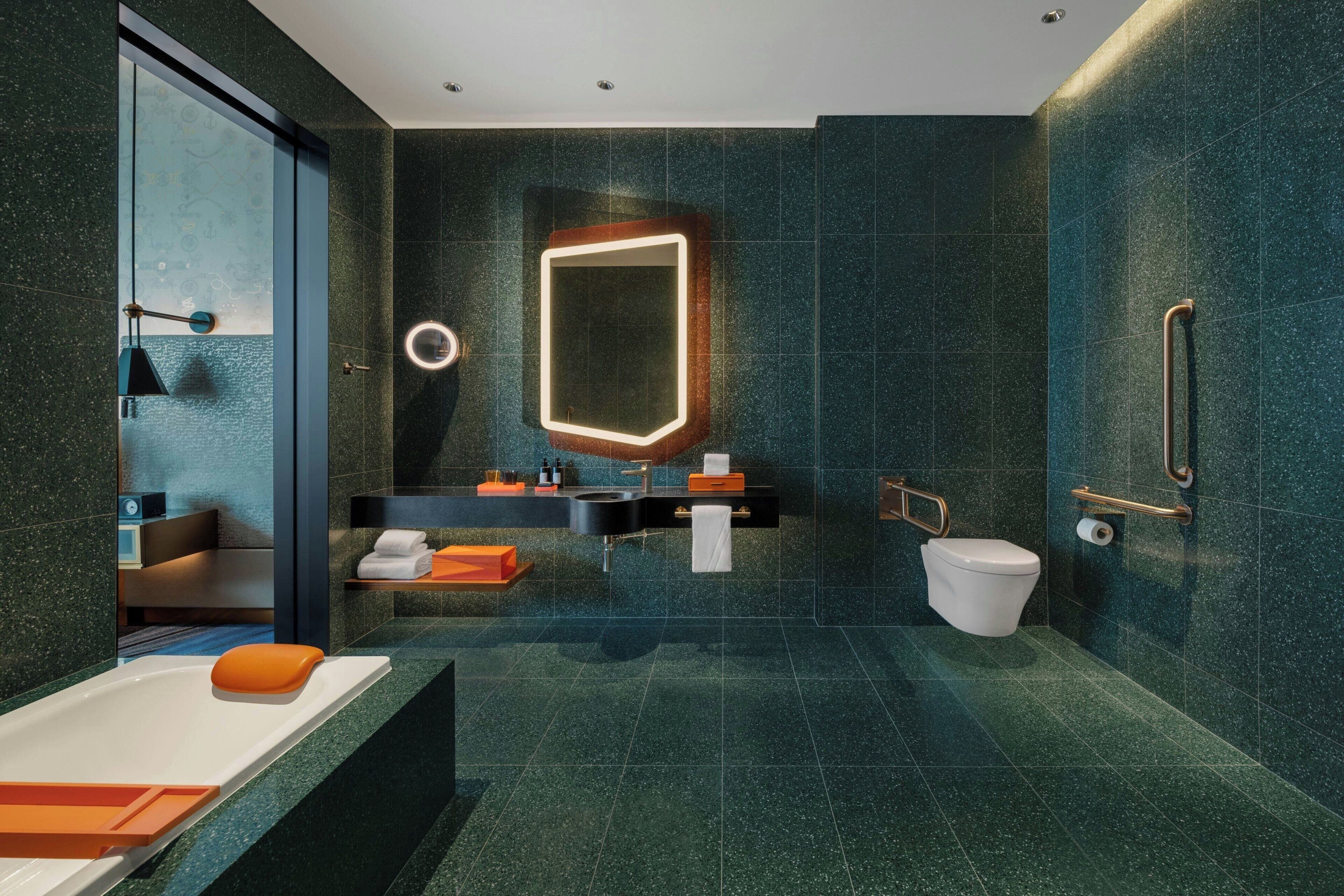 Un baño moderno con ducha de vidrio, un espejo grande, un inodoro y un lavabo con toallero.