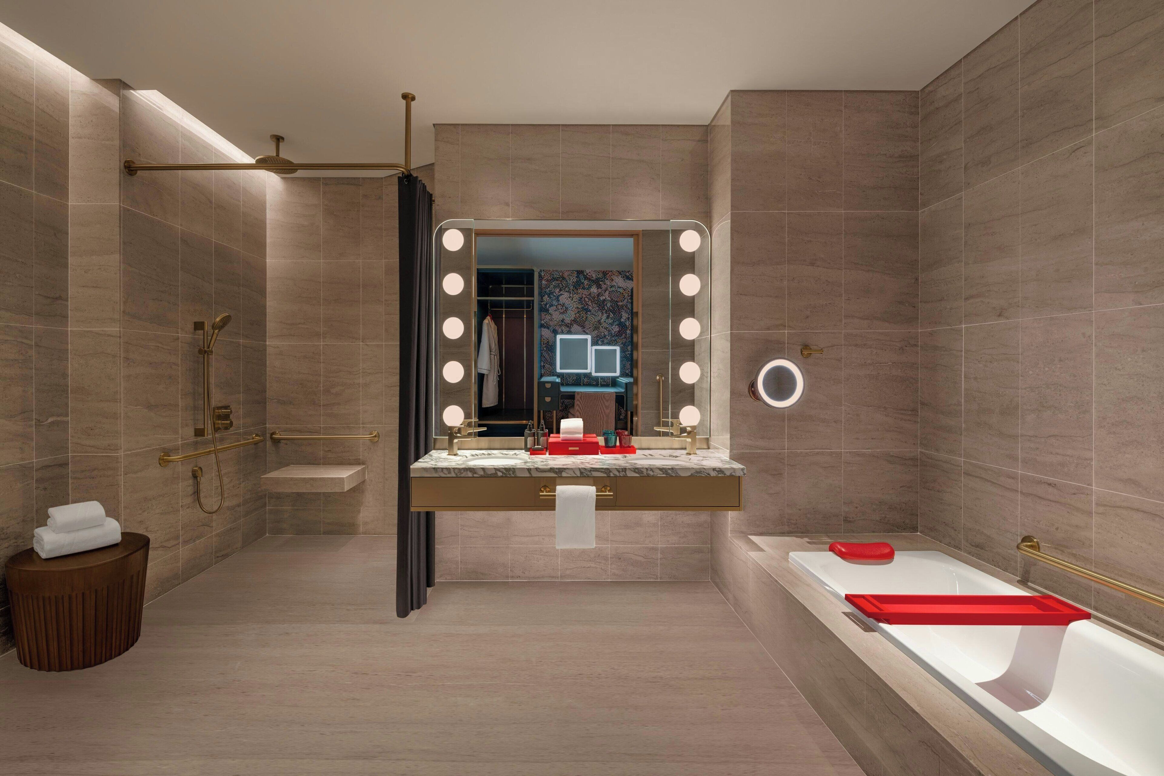 A modern bathroom with a vanity, a bathtub, and a large mirror with lights.