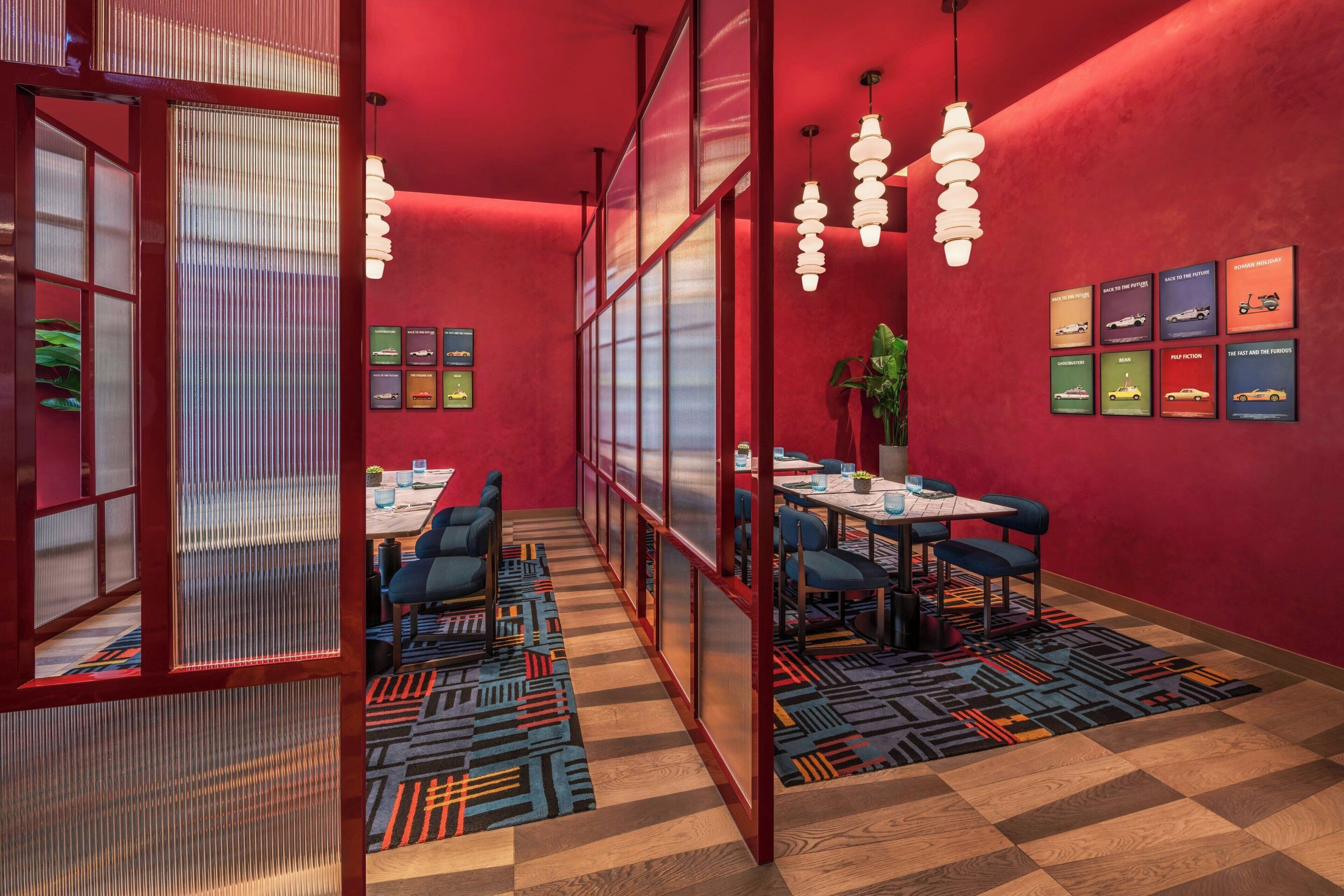 A modern conference room with red walls, patterned carpets, and a long table with chairs.