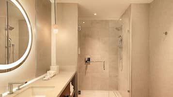 Un baño moderno con un espejo grande, un lavabo y una zona de ducha.