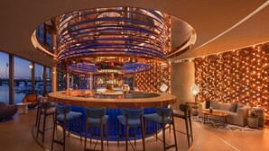 A modern bar area with a circular bar, seating, and a city view. - W Sydney (Sydney)