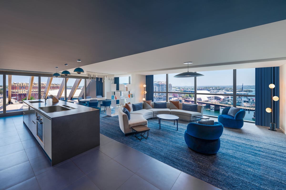 A modern living room with a kitchen area, large windows, and a city view.