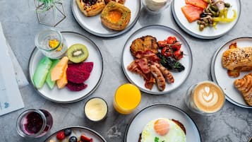 A variety of breakfast dishes including pancakes, eggs, bacon, and pastries on plates.