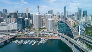 A cityscape with modern high-rise buildings, a distinctive curved building, and a marina with boats. - W Sydney (Sydney)