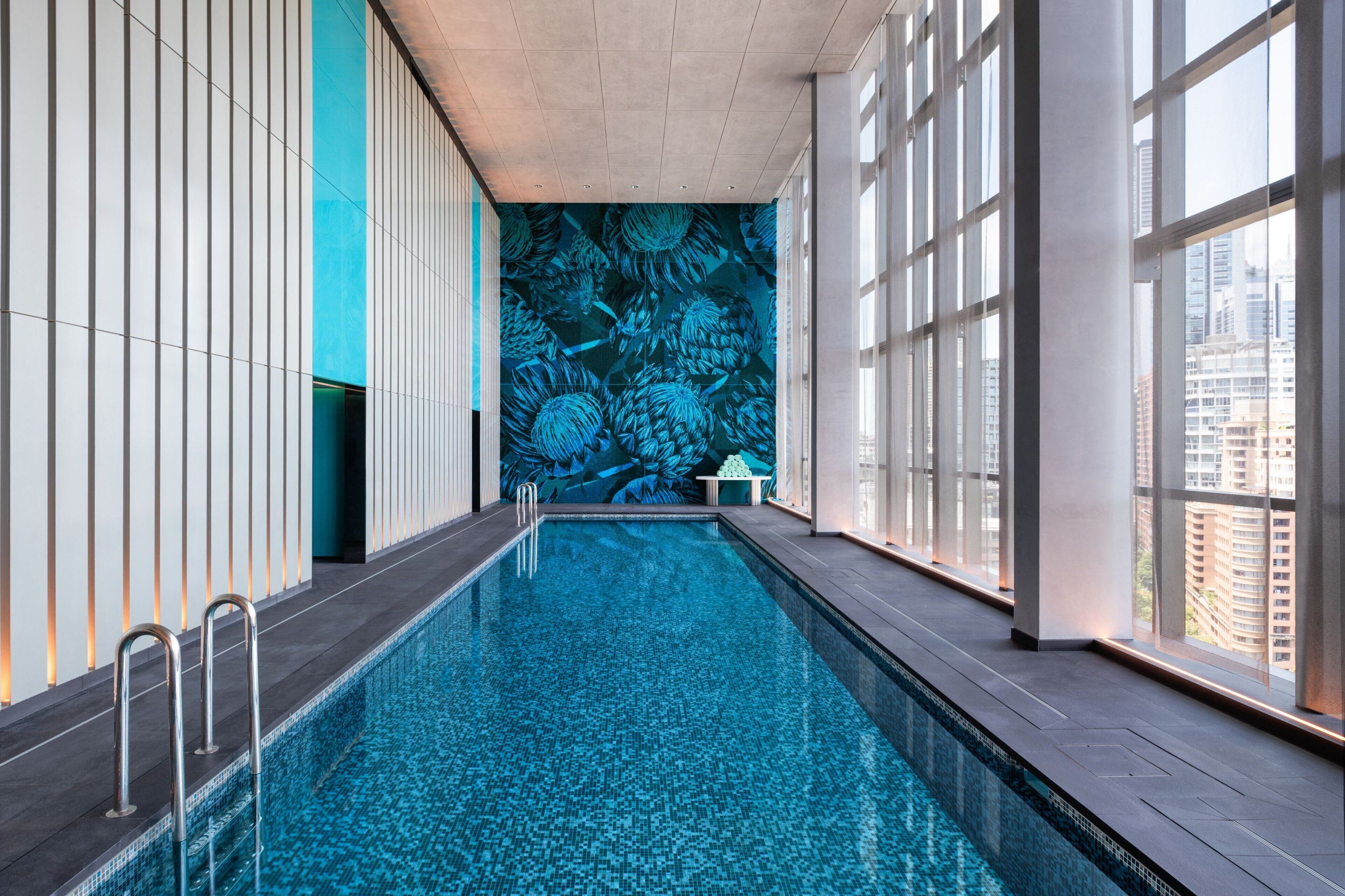 An indoor swimming pool with a tiled floor and a wall mural.