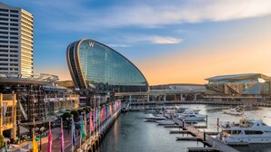 A waterfront marina with modern buildings, including a curved glass structure with a 'W' logo, and a high-rise building in the background. - W Sydney (Sydney)