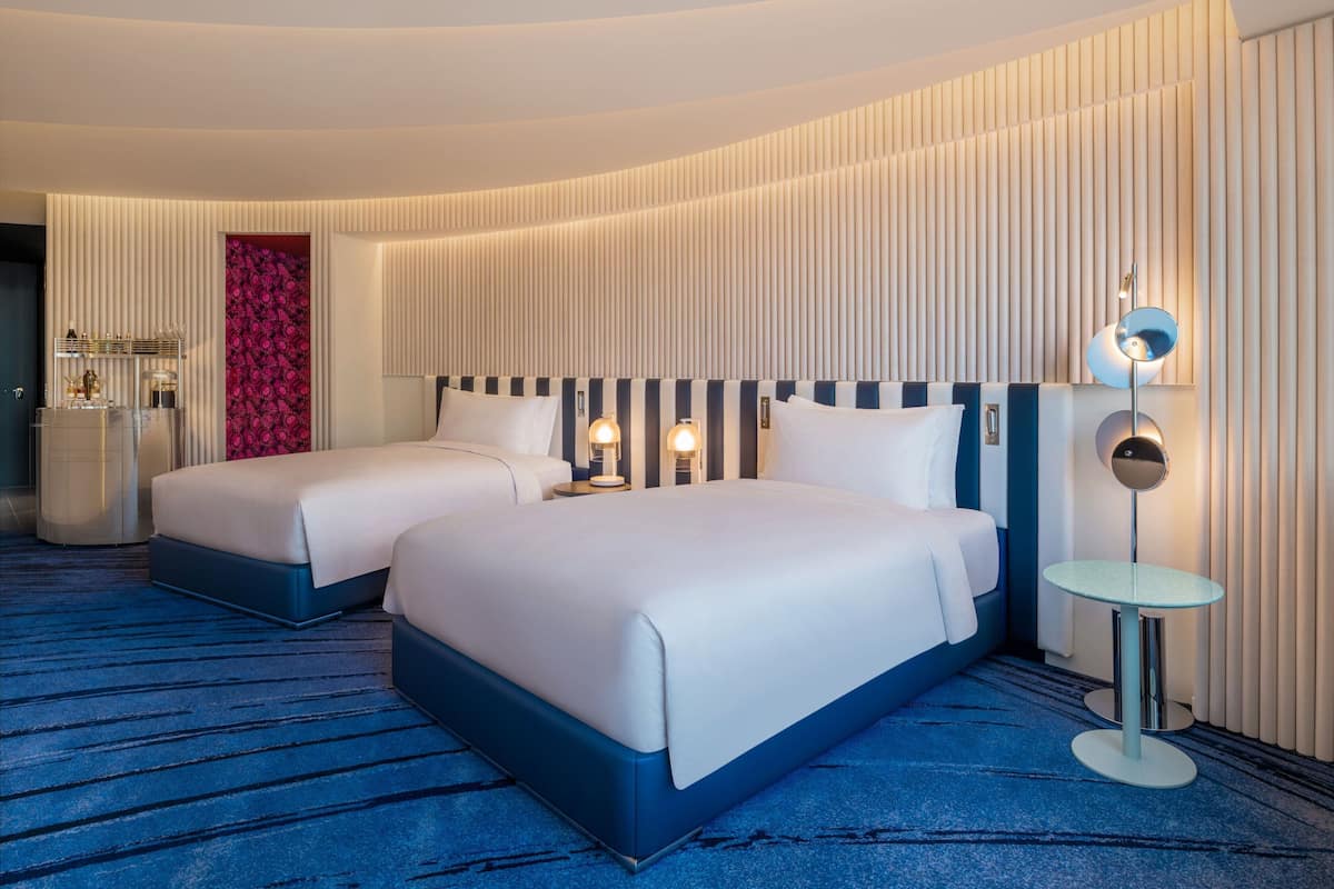 A hotel room with two beds, a small round table, and a mirror.