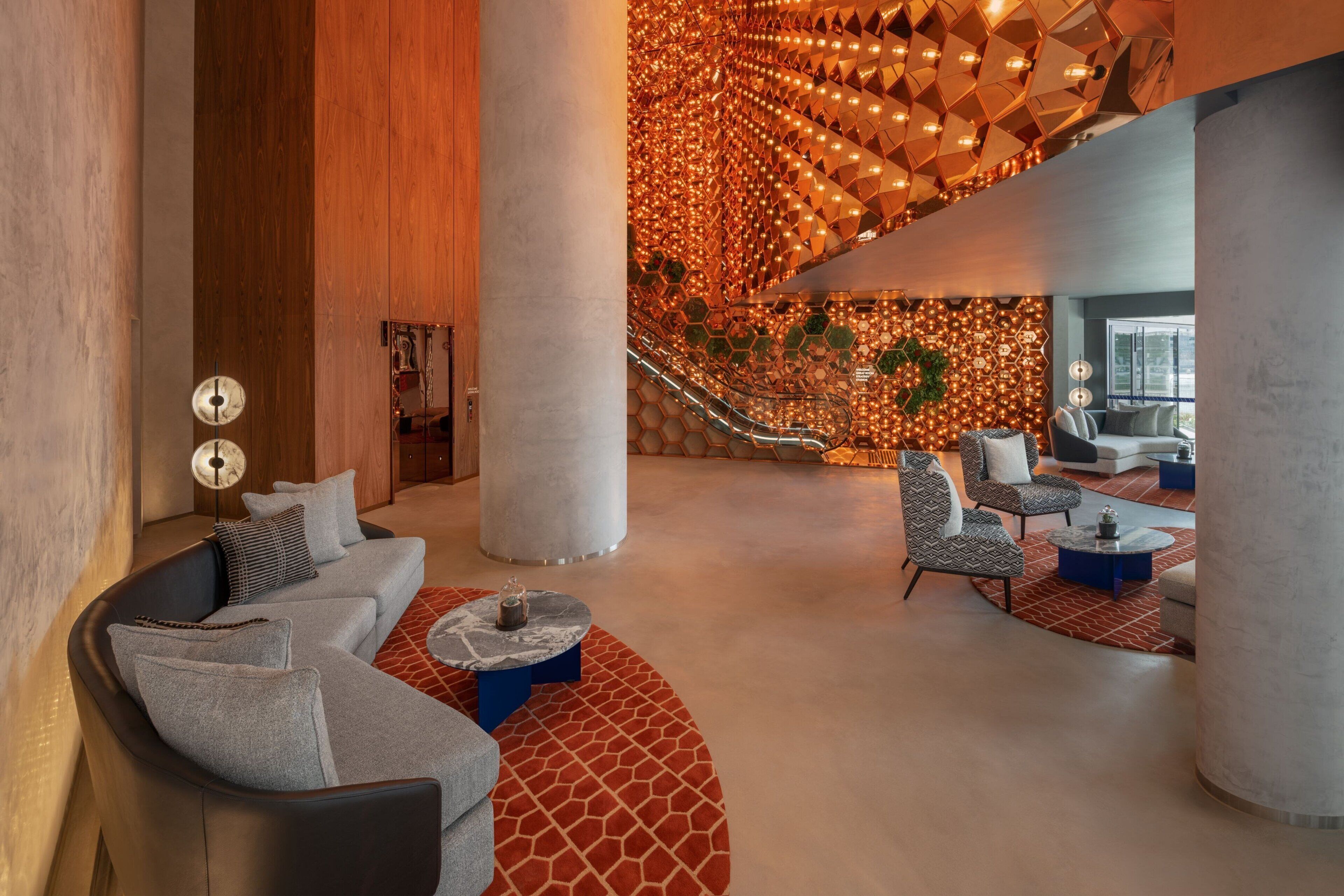 Un hallo espacioso con diseño moderno, que cuenta con una zona de estar curvo, una columna central grande y un muro con diseño.