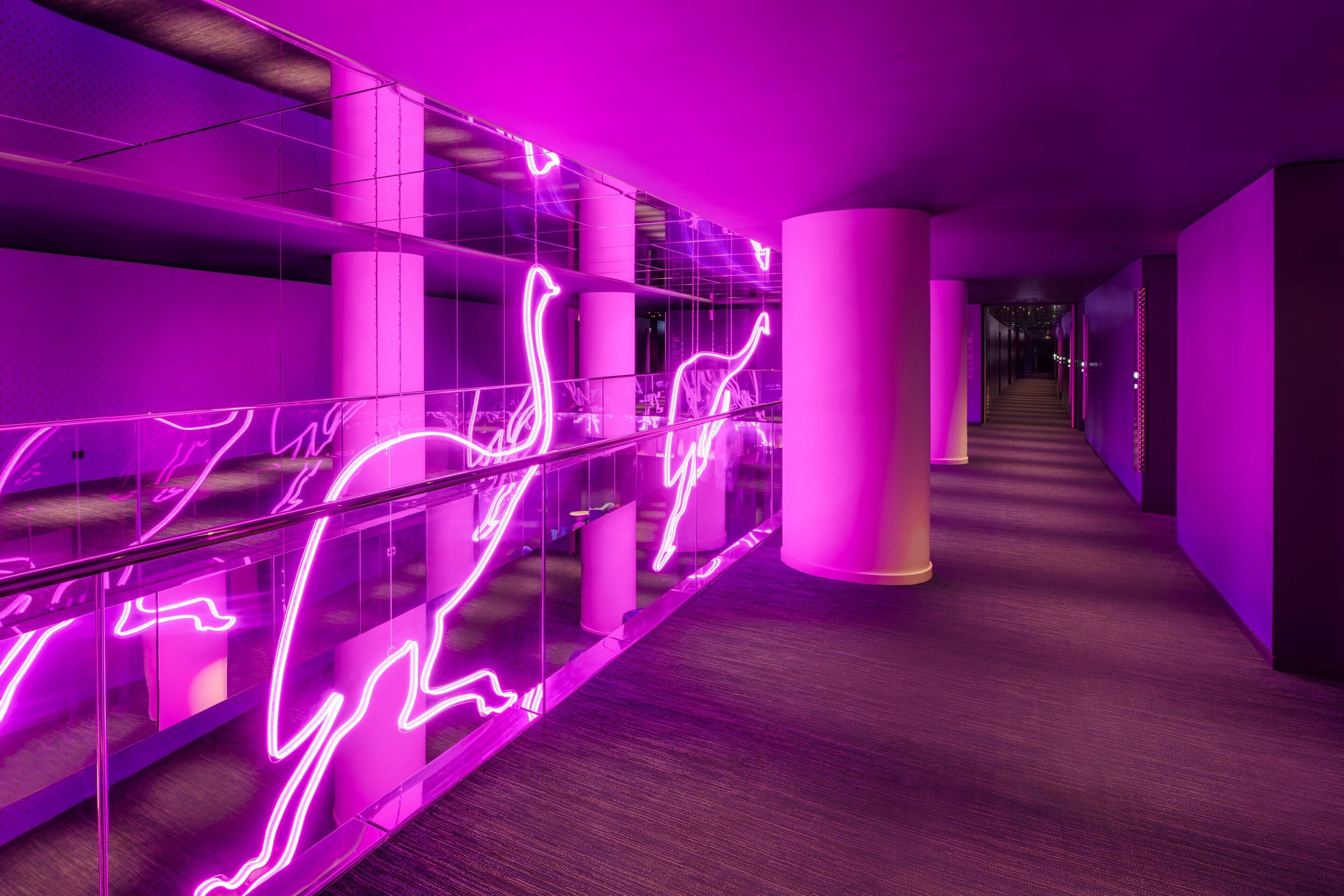 A modern hallway with glass railings and neon lights.