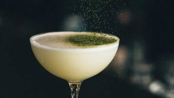 A martini glass with a green garnish on a dark surface.