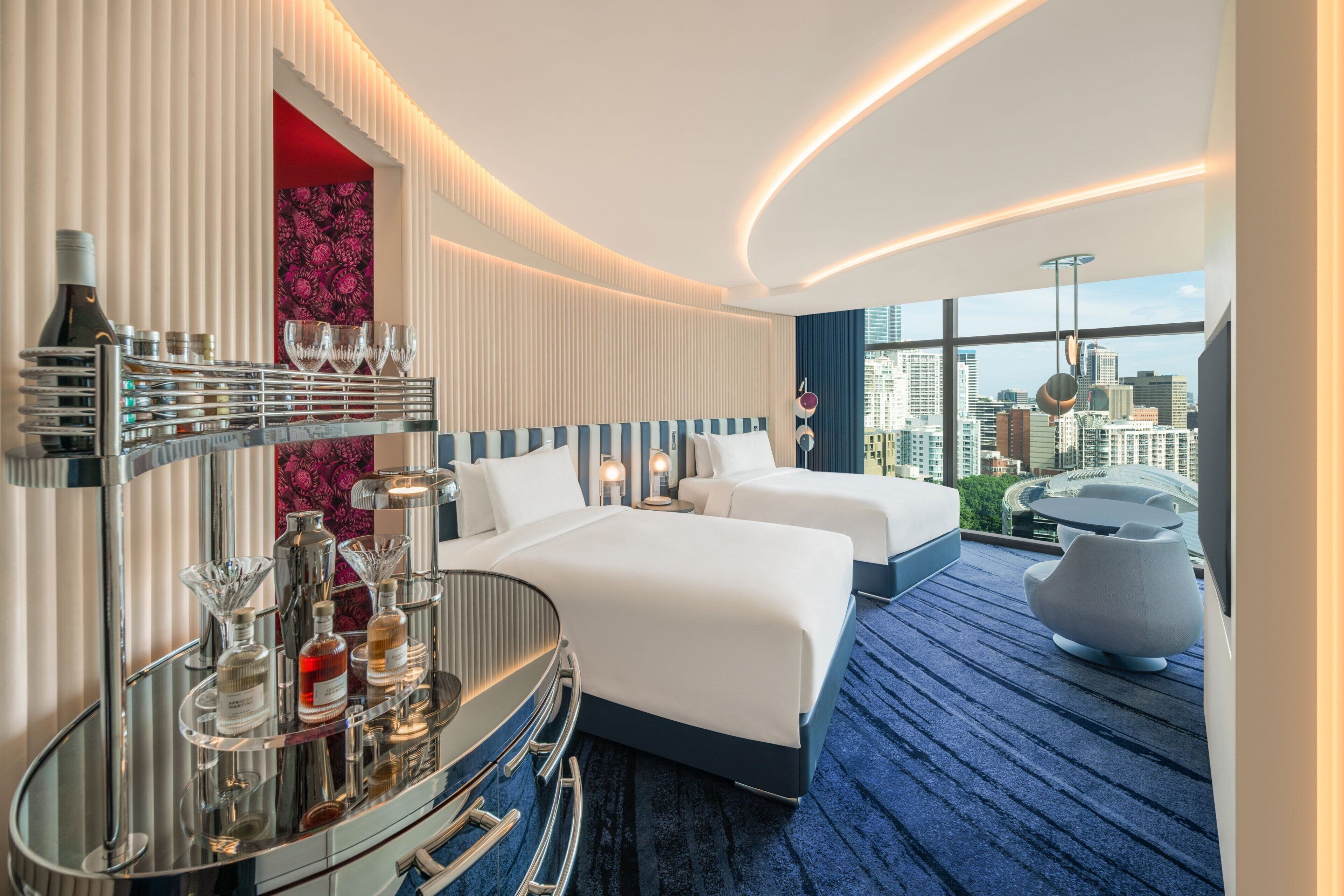 Une chambre d’hôtel moderne avec deux lits, un minibar et une vue sur la ville.