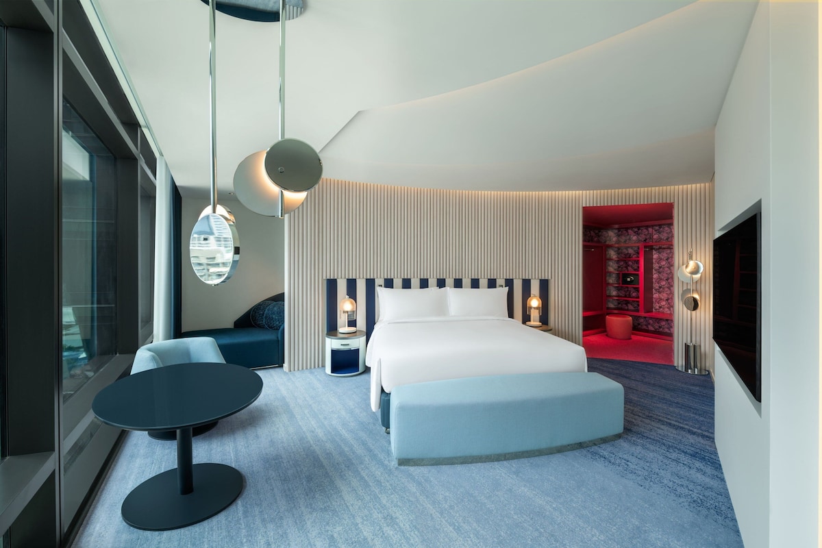 A modern hotel room with a large bed, a round table, and a seating area.