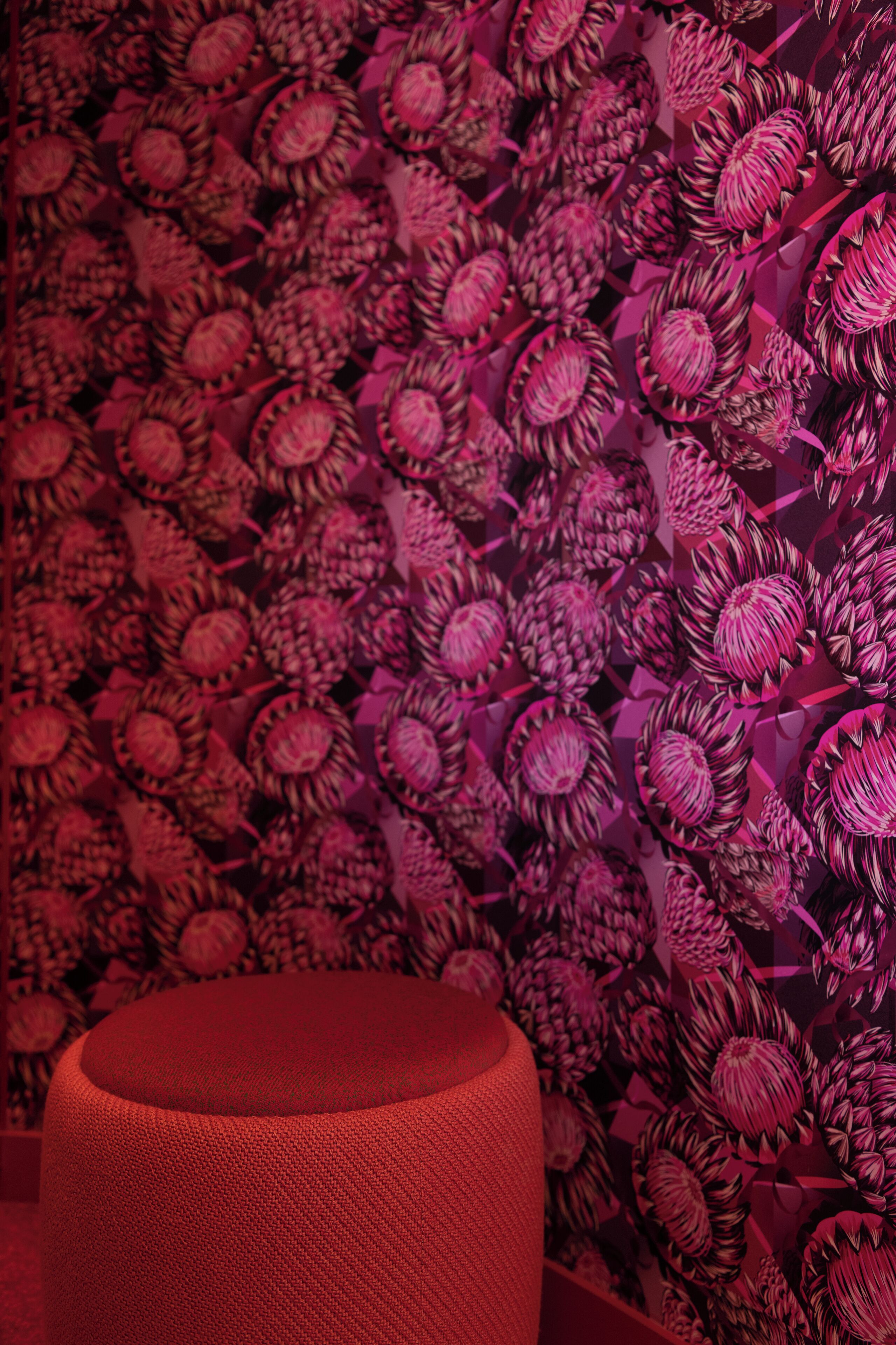 Une pièce avec un papier peint à motifs et un pouf rouge.