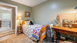 Un dormitorio con cama, mesita de noche, lámpara, cómoda y espejo.