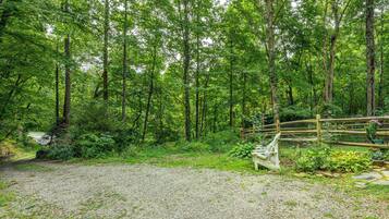 Un chemin de gravier qui mène à une zone boisée, avec un banc en bois et une clôture.