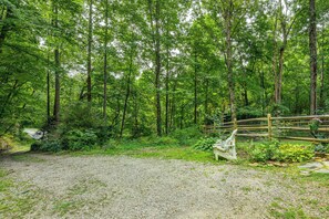 Un chemin de gravier qui mène à une zone boisée, avec un banc en bois et une clôture.