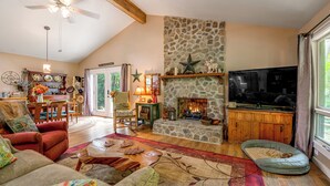 Una sala de estar acogedora con chimenea de piedra, televisor y comedor con muebles de madera.