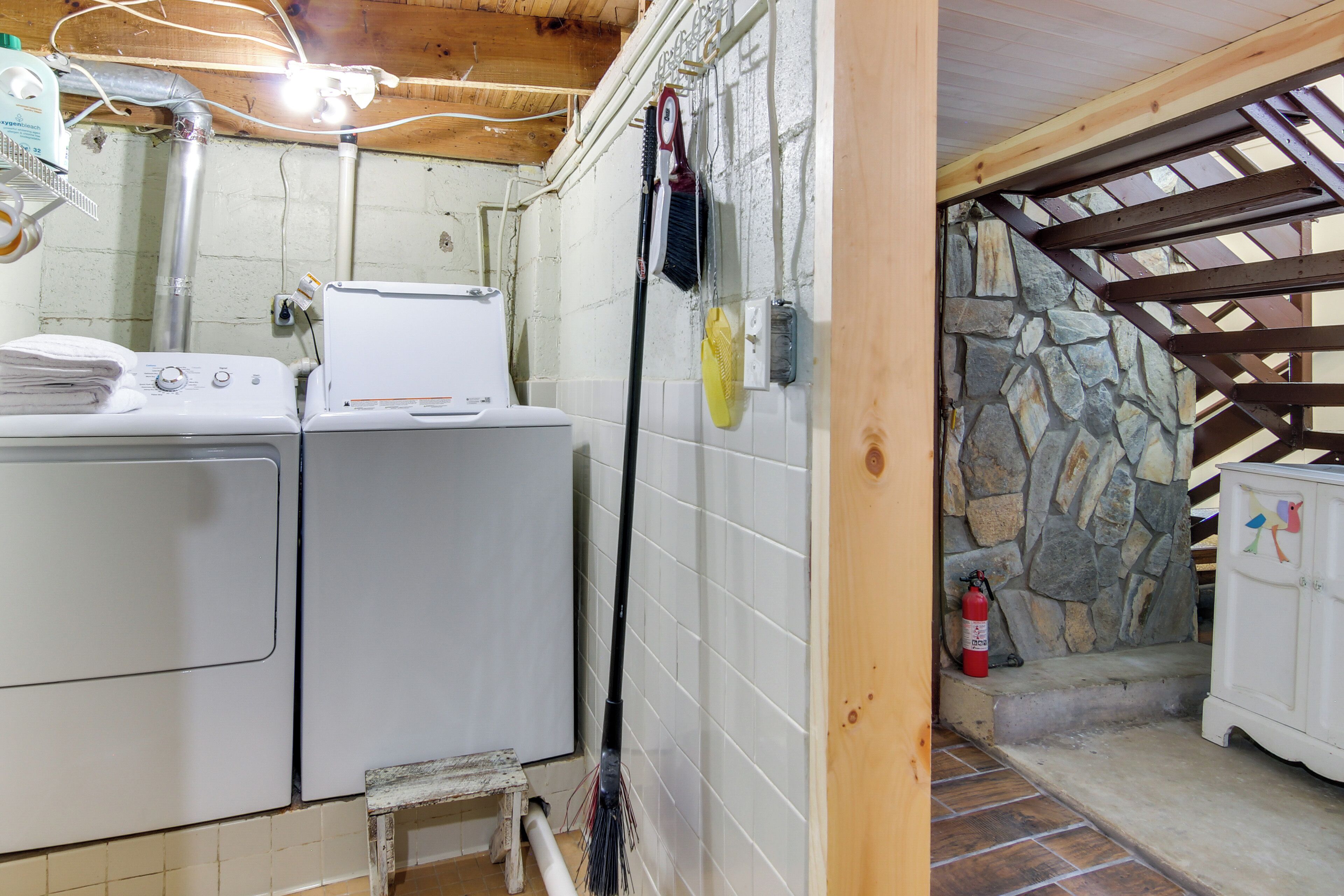 A laundry area with stacked towels, a washing machine, and a broom leaning against the wall.