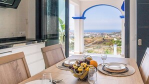 A dining table set with plates, glasses, and a fruit bowl, overlooking a scenic view. - Casa Mirador Azul Torrox by Ruralidays (Málaga)