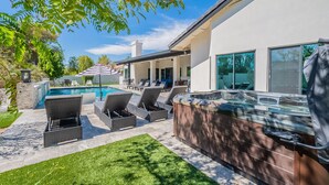 Eine moderne Terrassenanlage im Freien mit Whirlpool, Liegestühlen und Schwimmbad.