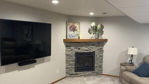A living room with a stone fireplace, a flat-screen TV mounted on the wall, and a sofa. - 2027 Oshkosh EAA rental — 4.5 miles from the AirVenture (Oshkosh)