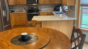 A kitchen with wooden cabinets, a granite countertop, a stainless steel refrigerator, a microwave, an oven, and a sink. - 2027 Oshkosh EAA rental — 4.5 miles from the AirVenture (Oshkosh)
