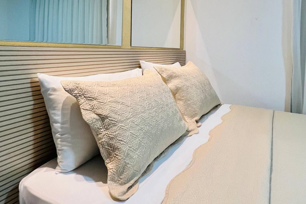 A neatly made bed with a headboard, pillows, and a blanket.