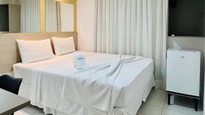 Ein Hotelzimmer mit Bett, Schreibtisch, Stuhl, Fernseher und einer Minibar.