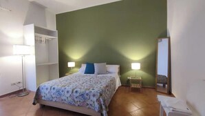 Een slaapkamer met een bed, twee bedlampen, een nachtkastje, een spiegel en een kledingkast.