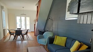 A modern living room with a blue sofa, a wooden coffee table, and a dining area with a table and chairs. - Maison Proche Centre Ville de Moulins (Yzeure)