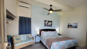 Une chambre à coucher comprenant un lit, un canapé, un ventilateur de plafond, un appareil de climatisation et une carte du monde accrochée au mur.