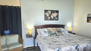 Una camera da letto con un letto, due comodini, una lampada, una sedia e una mappa del mondo appesa al muro.