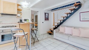 Una cocina compacta con estufa a gas, microondas y un pequeño comedor con sillas.