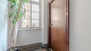 Un pasillo con una planta en maceta, una puerta de madera y una ventana.