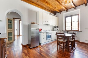 A kitchen with white cabinets, a stainless steel refrigerator, and wooden flooring.