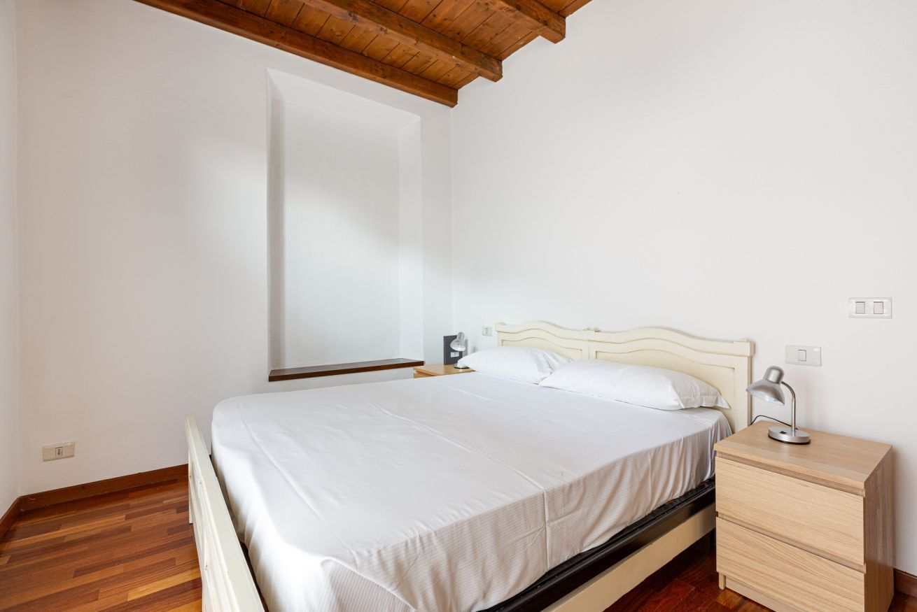 A bedroom with a bed, bedside table, and a nightstand.