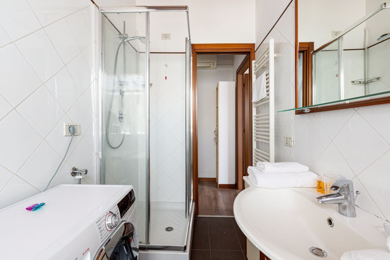 A bathroom with a glass shower enclosure, a white sink, and a mirror above the sink.