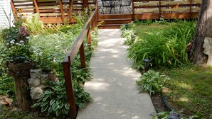 A garden pathway with a wooden fence, various plants, and a stone owl sculpture.