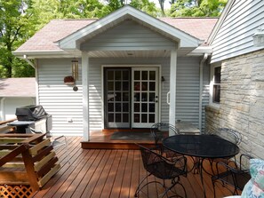 A covered patio with a grill, outdoor seating, and a door leading to a garage. - The Stone House/New Listing! Nov. 1 - May 31st, rent 3 Get one FREE! WI-FI (Fish Creek)