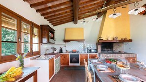 Una cocina con armarios de madera, una mesa de comedor preparada para cuatro personas y un horno de ladrillo.