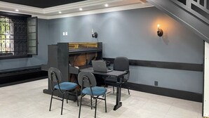 A modern room with a desk, two chairs, a laptop, and a staircase. - Suite P at Piano Coliving POA (Independência Porto Alegre)