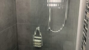 A modern shower enclosure with a glass door, a handheld showerhead, and a handheld shower attachment. - Suite P at Piano Coliving POA (Independência Porto Alegre)