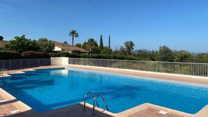 Ein rechteckiger Swimmingpool mit einer Metallleiter im Vordergrund, umgeben von einem weißen Zaun.