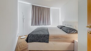A modern bedroom with a bed, a floor lamp, and a window with curtains. - Charming Apartment With Balcony With the sea View (Split)