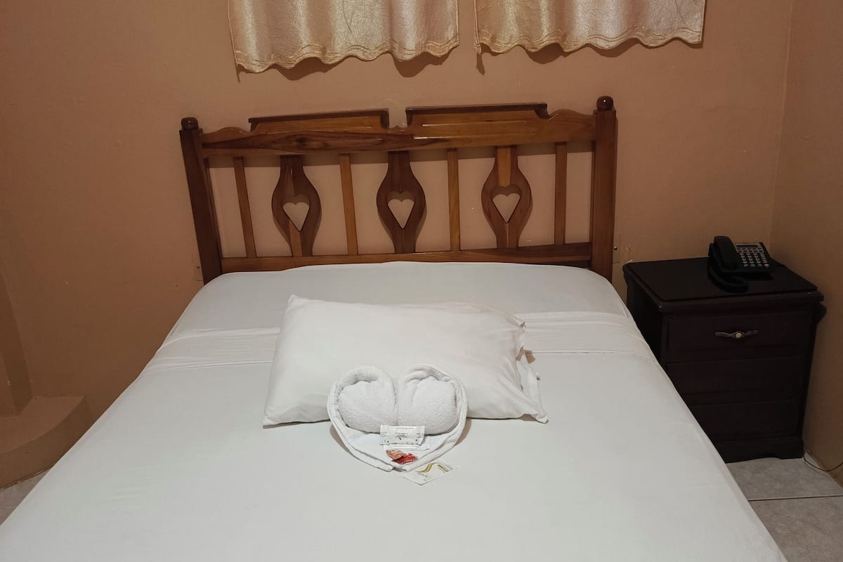Un letto rifatto con lenzuola bianche e un’accogliente composizione di cuscini a forma di cuore.