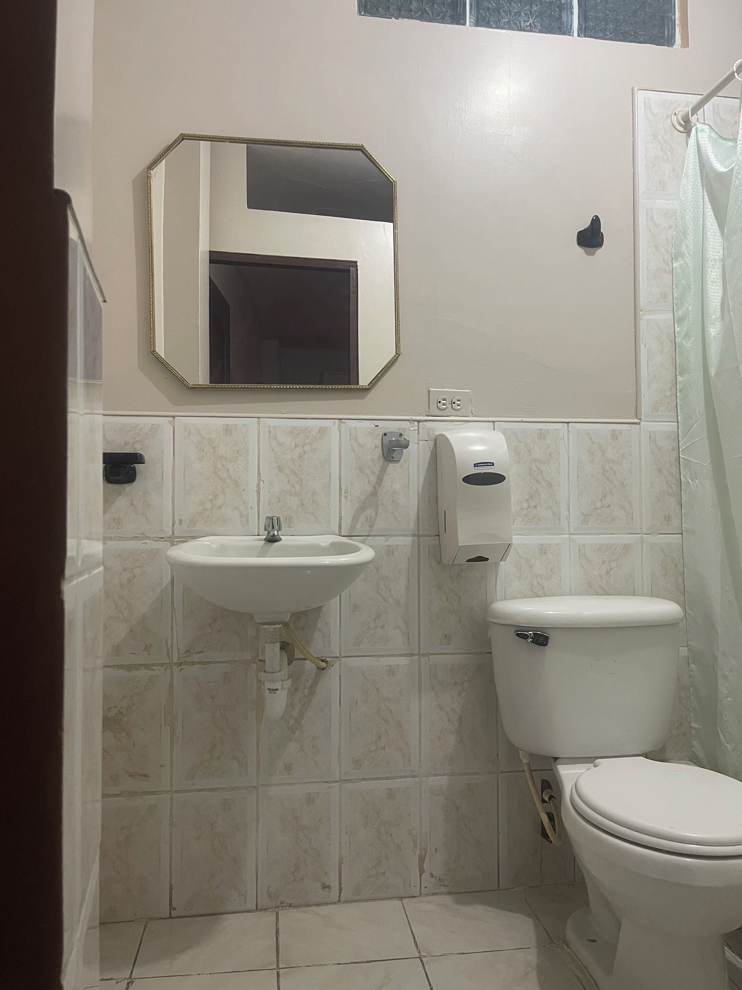 A bathroom with a sink, toilet, and a mirror.