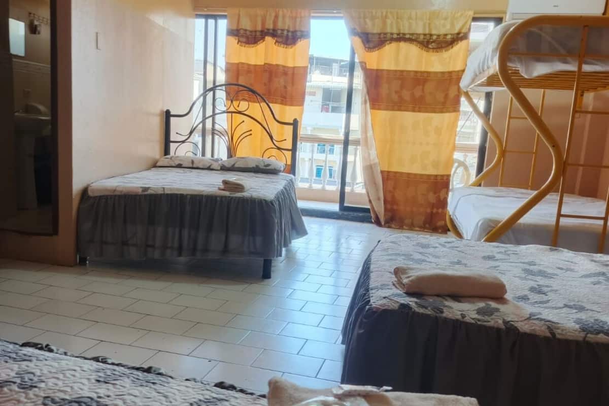 Camera d'albergo con due letti, un balcone e una sedia.